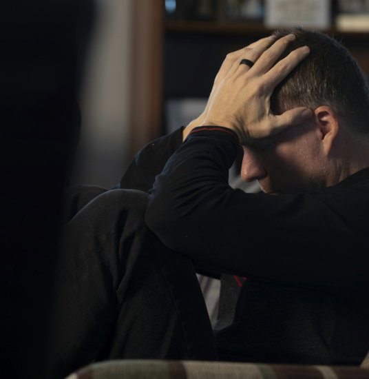 a man sitting on a couch holding his head in his hands